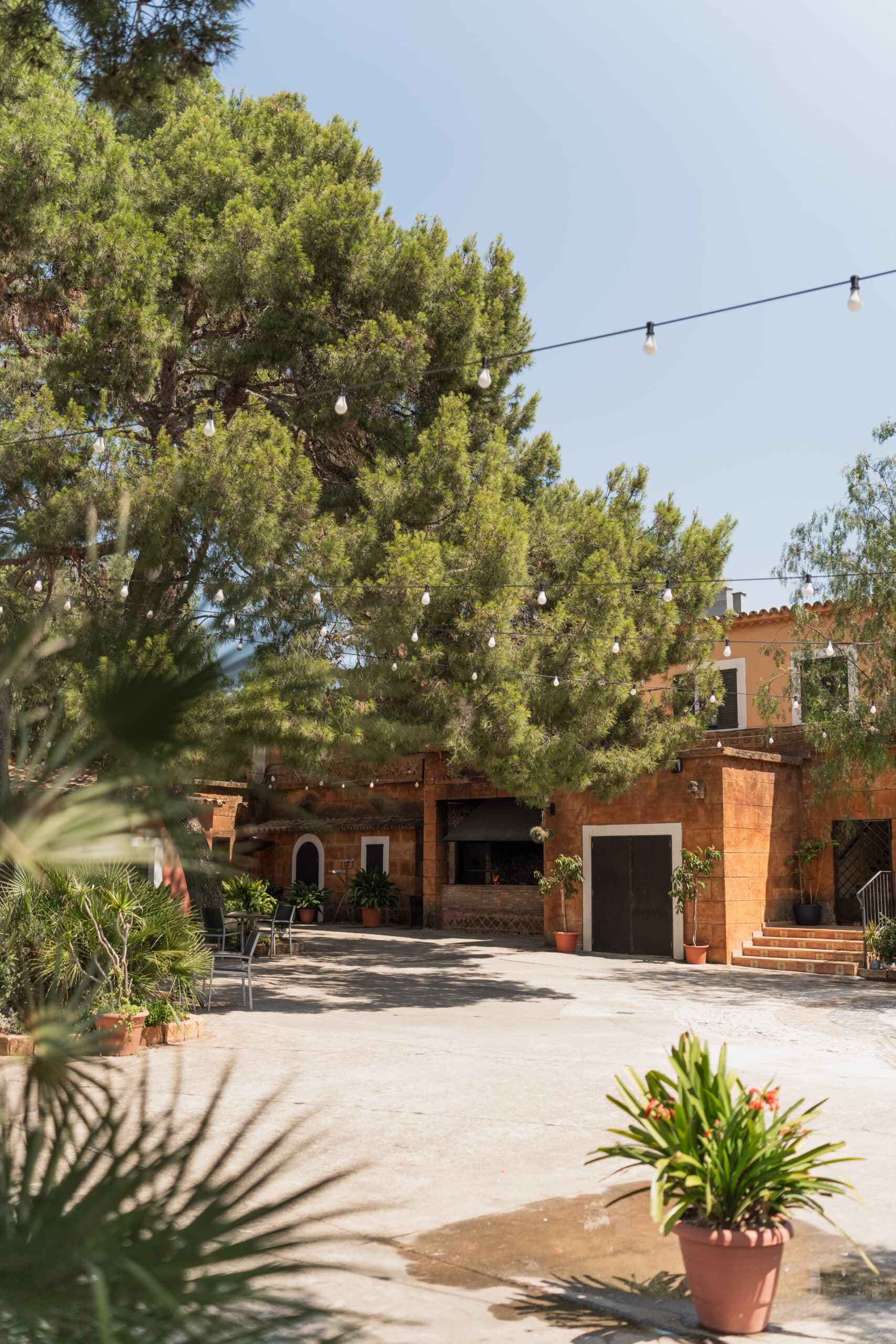 jardin del restaurante molí des comte con una parilla al fondo y unas mesas y sillas con mucha naturaleza alrededor